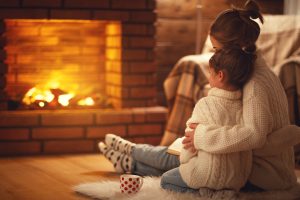 family mother and child hugs and warm on winter evening by fireplace family mother and child daughter hugs and warm on winter evening by fireplace